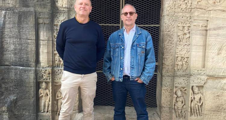 Twee mannen die voor een historische stenen muur staan.