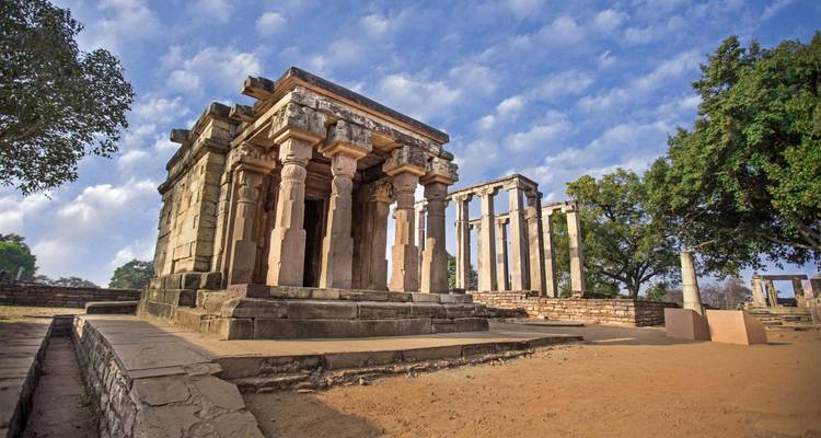Oude structuur met zuilen en omringende groen.