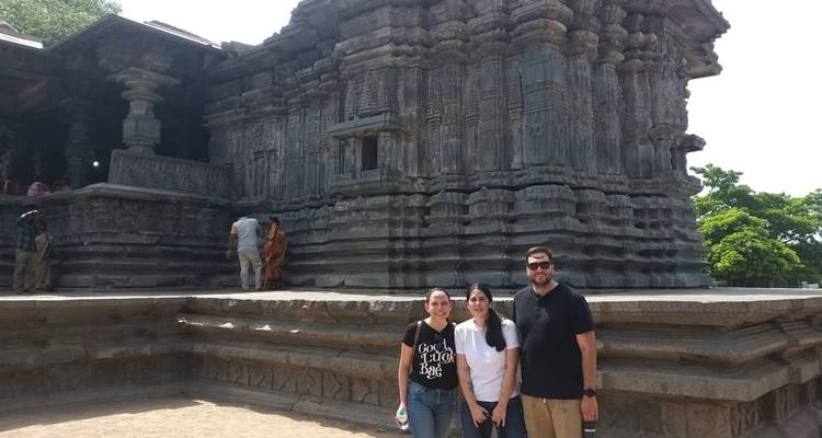 Drie mensen die voor een oude stenen tempel staan.