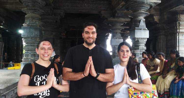 Drie mensen met traditionele tekens op hun voorhoofd, poserend in een tempel.