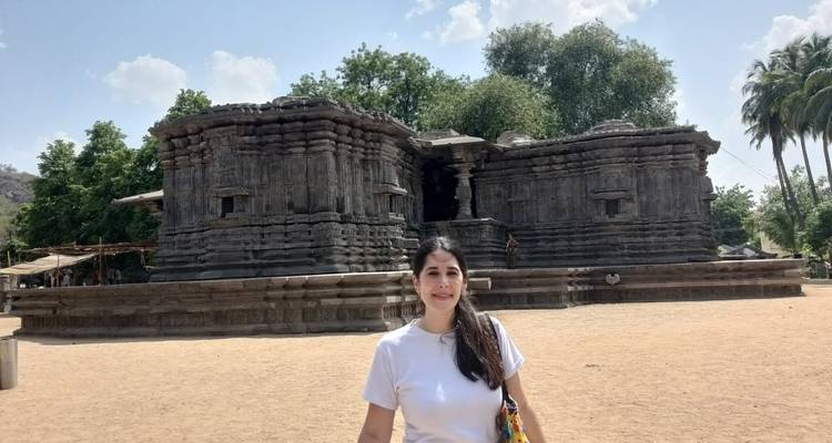 Een persoon die poseert voor een oude tempelstructuur.