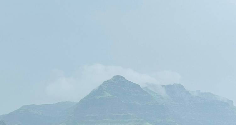 Pico de montaña brumosa emergiendo a través de una neblina azul pálida con detalles mínimos.