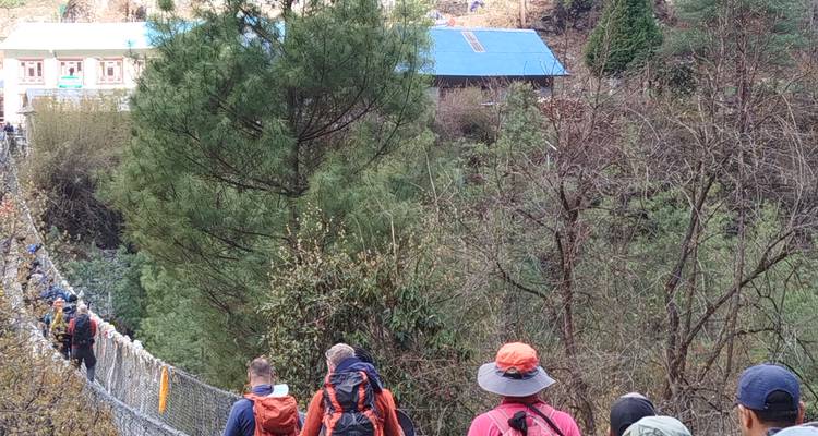 Wanderer, die auf einem Pfad gehen, mit Gebäuden im Hintergrund.