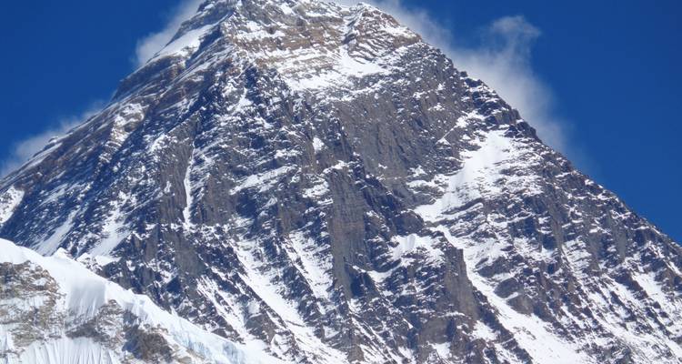 Nahaufnahme eines schneebedeckten Berggipfels mit klarem blauen Himmel.
