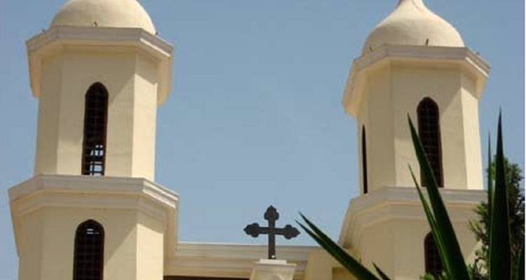 Zwillingskuppelkirche mit einem Kreuz vor blauem Himmel.
