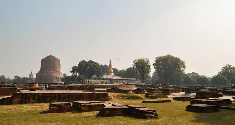 Ruïnes met een grote stupa op de achtergrond.