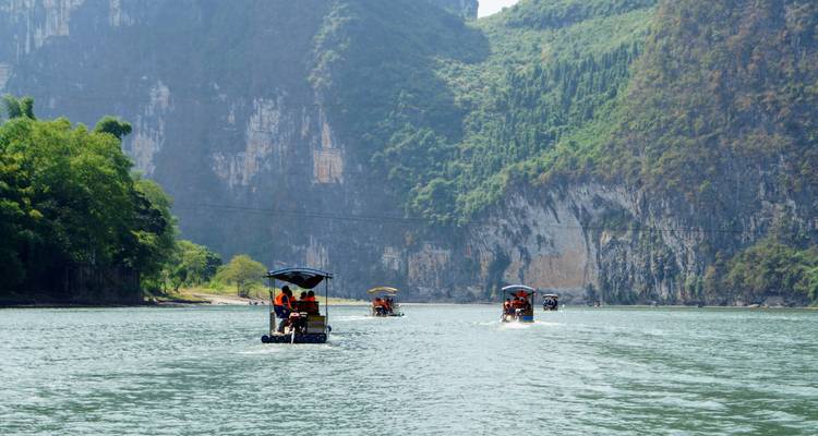 Turistas en barcos en un río con acantilados.