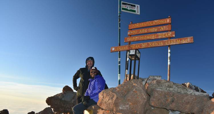 People at the summit of Mount Kenya with a sign.