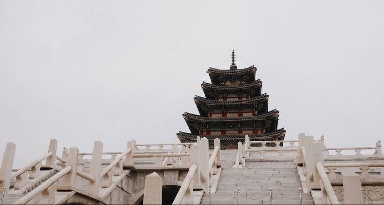 Pagode au sommet d'un escalier avec un ciel nuageux en arrière-plan.