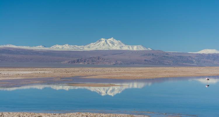 Montañas cubiertas de nieve reflejadas en agua cristalina y tranquila.