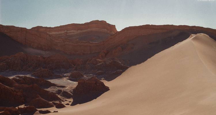 Paisaje desértico dramático con dunas de arena y formaciones rocosas.
