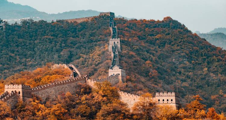 Gran Muralla China serpenteando a través del paisaje montañoso con follaje otoñal.