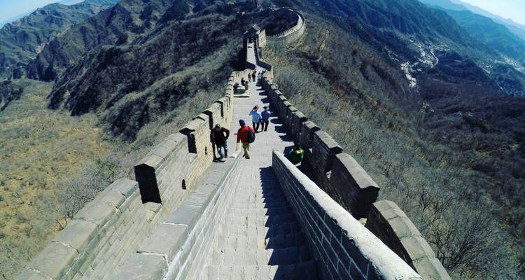 Des gens marchant sur la Grande Muraille de Chine qui s'étend à travers un terrain montagneux.