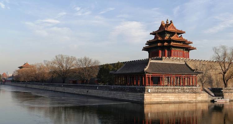 Architecture chinoise traditionnelle le long d'une voie navigable entourée d'arbres.