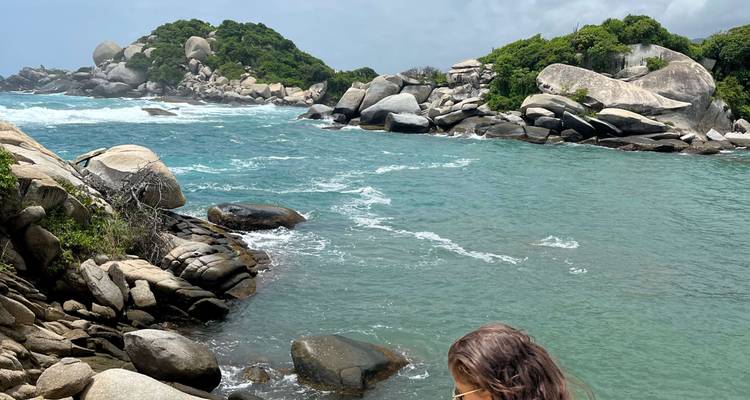 Bahía turquesa con rocas de granito y un viajero solitario admirando la vista.