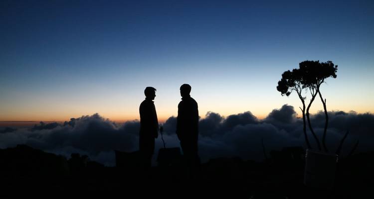 Siluetas de dos personas con un cielo al atardecer.