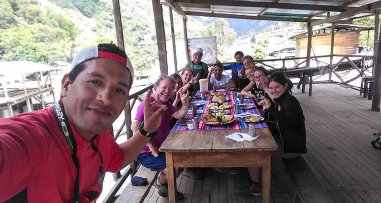 Group of people having a meal on a wooden deck in the mountains.