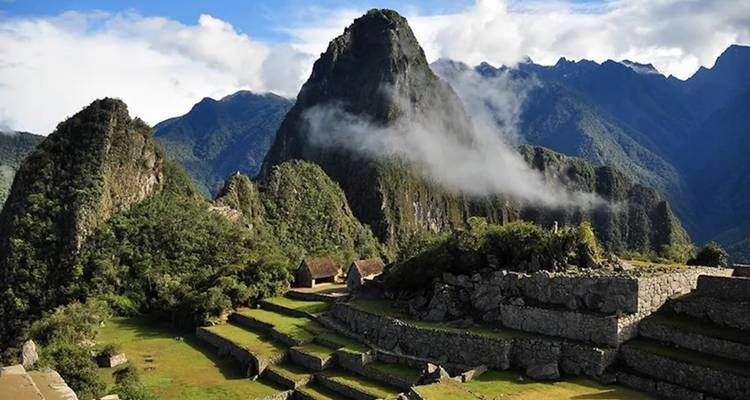 Overview of ancient ruins and terraces with mountainous background.