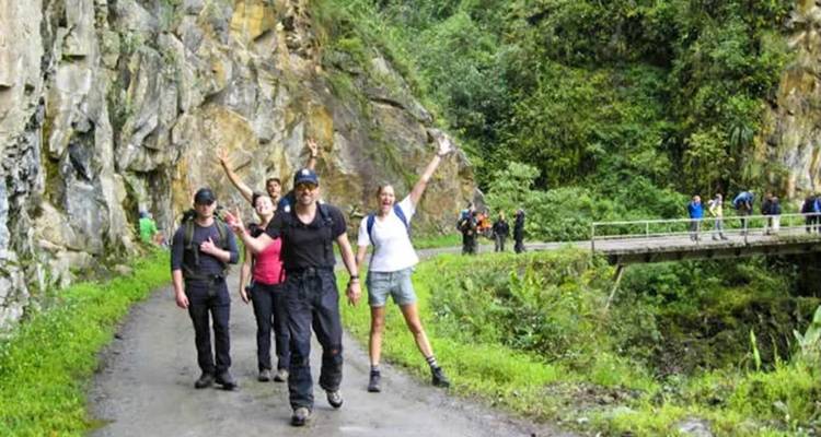 Group of people hiking along a green mountain path.