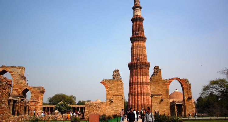Besucher, die in der Nähe des Qutub Minar spazieren gehen, einem alten Steinturm.