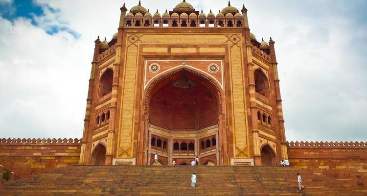 La majestuosa Buland Darwaza elevándose sobre amplios escalones de piedra con algunos visitantes que ilustran la escala.
