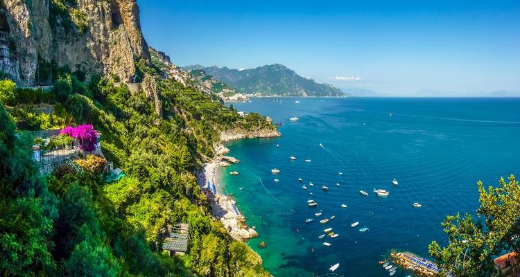 Vue panoramique d'un littoral avec une mer bleue cristalline et une végétation luxuriante.