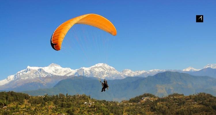 Parapentiste dans le ciel avec des montagnes en arrière-plan, filigrane présent.