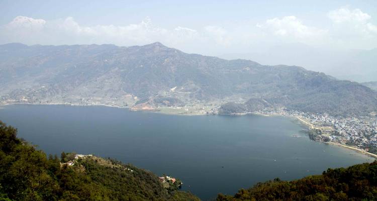 Vista panorámica de un amplio lago azul rodeado de colinas ondulantes y pueblos dispersos.