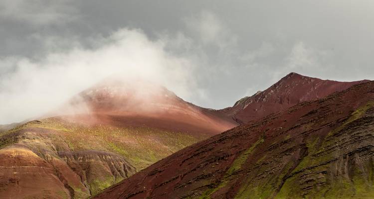 Nevelige bergen met kleurrijke gelaagdheden en bewolkte luchten.