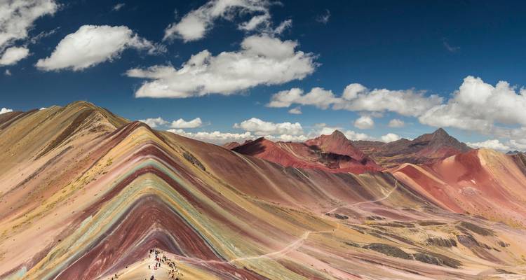 Panoramisch uitzicht op Rainbow Mountain onder een heldere blauwe hemel.