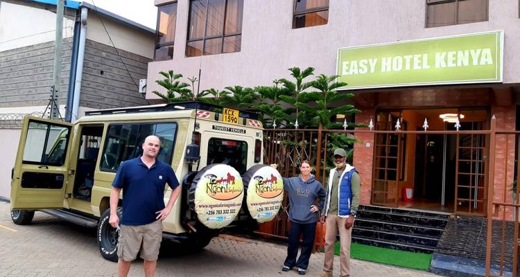 Touristen posieren neben einem Fahrzeug am Easy Hotel Kenya.