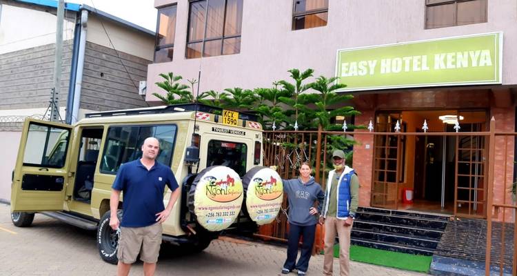 Menschen stehen vor dem Easy Hotel Kenya mit einem Safari-Fahrzeug.