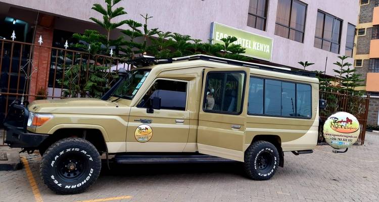 Ein Safari-Fahrzeug, das auf einer asphaltierten Straße geparkt ist, mit sichtbarem Logo und Text.