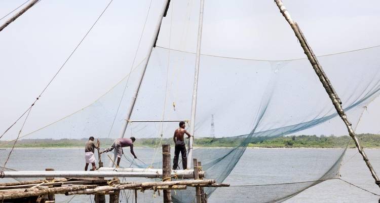 Fishermen working on large nets on a water body.