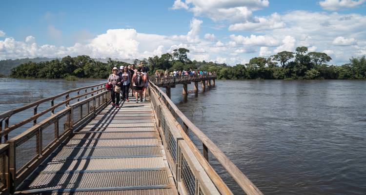 Tourists walking on a bridge over a river.