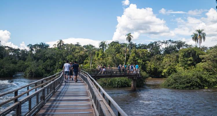 People walking on a wooden bridge over water.