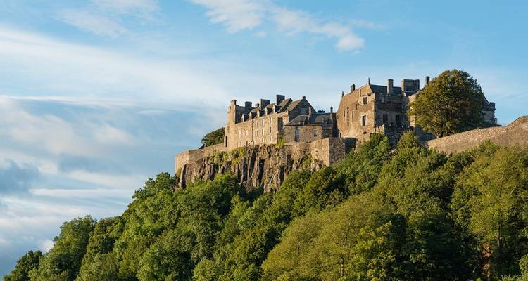 Château historique sur une colline entouré de verdure.