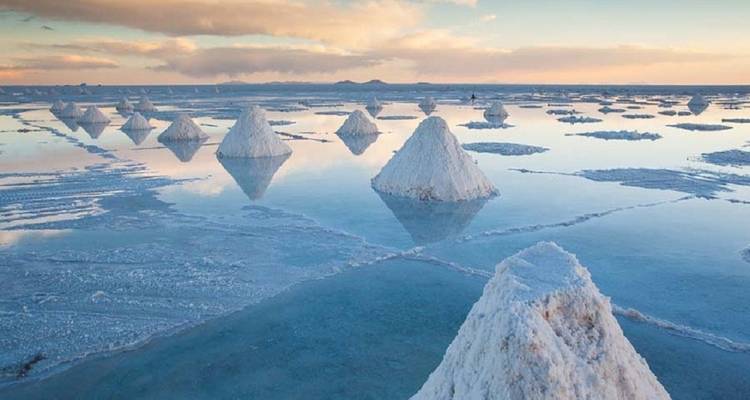 Blick auf Salzebenen bei Tagesanbruch mit pyramidenförmigen Salzhaufen.