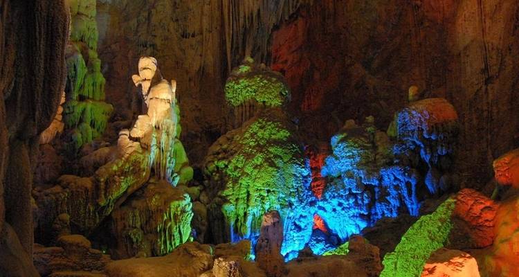 Bunte Stalaktiten und Formationen in einer beleuchteten Höhle.