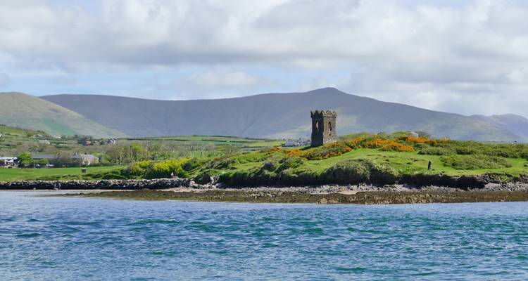 Château au bord de l'eau avec des montagnes en arrière-plan.