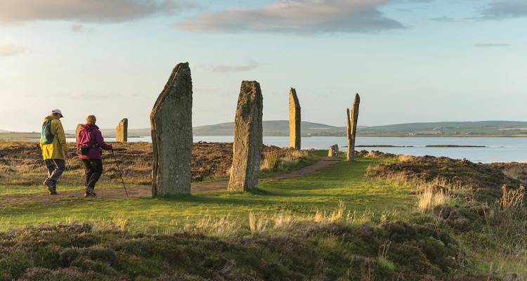 Tourists walking among the Standing Stones of Stenness with a scenic background.