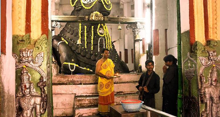 Gruppe von Menschen in der Nähe einer großen Gottesstatue in einem Tempel.