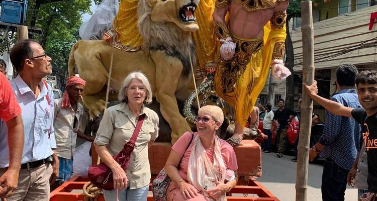 Twee vrouwen in een processie met grote beelden.