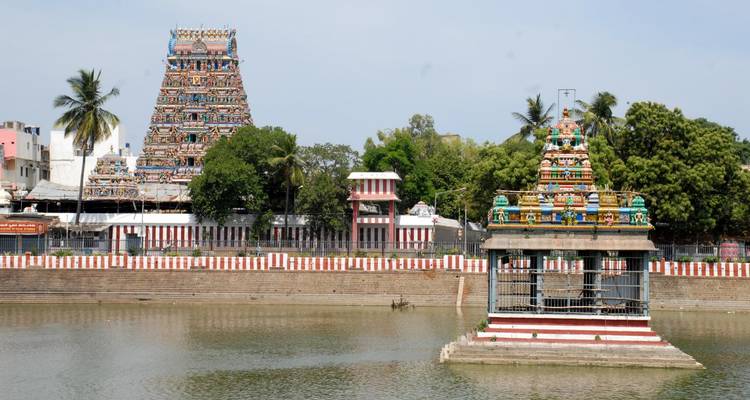 A colorful Hindu temple complex by a water body.