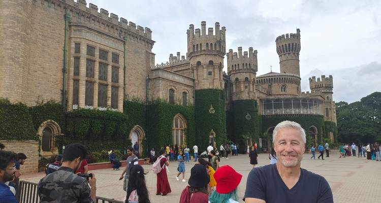 Menschenmenge vor dem Bangalore-Palast mit einem Mann, der in die Kamera lächelt.