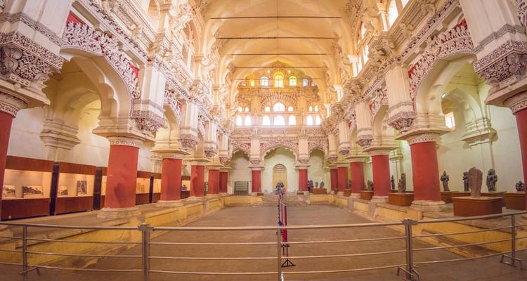 Vue intérieure d'un grand hall orné avec des colonnes rouges et des motifs complexes.