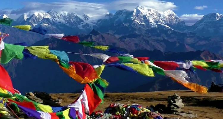 Bunte Gebetsfahnen mit schneebedeckten Bergen im Hintergrund.