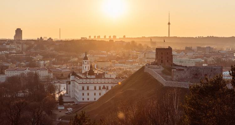 Zonsondergangzicht over een stad met historische gebouwen en een televisietoren.