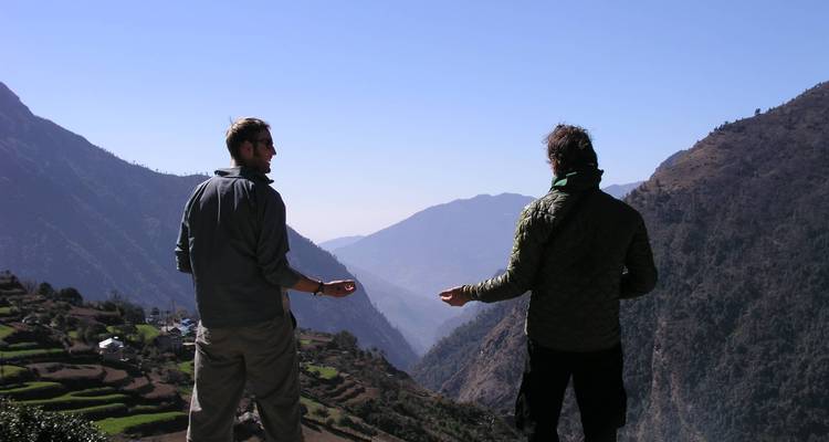 Dos personas disfrutando de una vista sobre un valle de montaña.