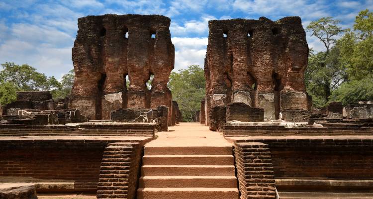 Las antiguas ruinas de ladrillos de un complejo palaciego real se alzan bajo un cielo parcialmente nublado.